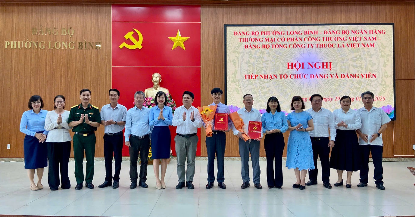 '''A group of people standing in front of a large poster

Description automatically generated'''