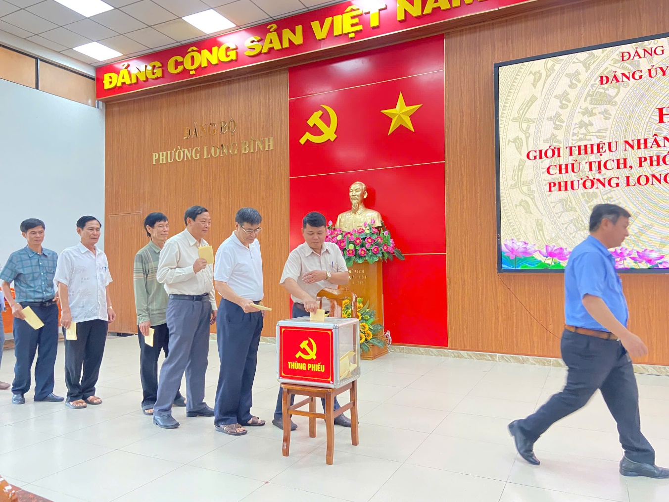 '''A group of people standing in a room

Description automatically generated'''